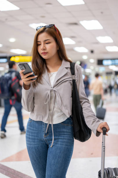 istock A female passenger is checking her flight information on her smartphone while walking in the airport 2049418788