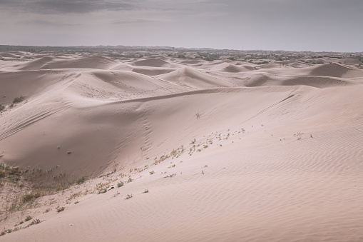 Badain Jaran Desert in Inner Mongolia, China, the third largest desert in China, with the tallest stationary dunes on Earth blue sky, white clouds in background, black and white