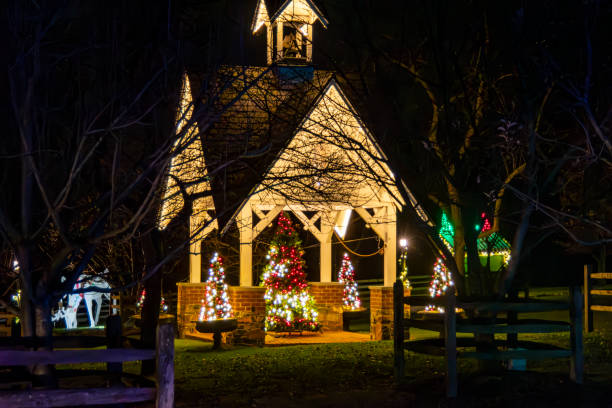 istock Illuminated Night View Of Small Chapel Surrounded By Multiple Christmas Trees Decorated With Lights 2049472986