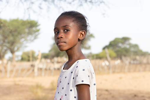 african girl with a proud expression , in the village, standing in front of the kraal with small livestock