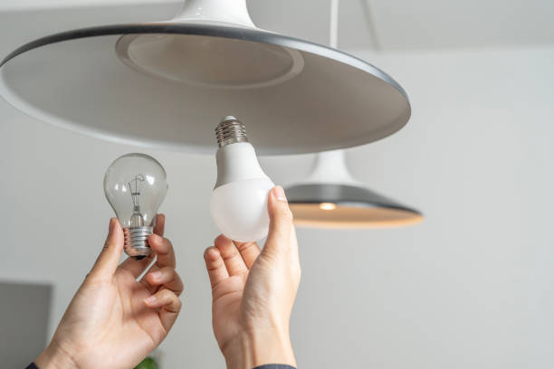 istock Asian people replace fluorescent light bulbs (CFL) with new LED bulbs. Female hands screw in an energy-saving LED light bulb. 2049505272