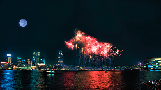Fireworks display at Victoria Harbor in Hong Kong on a moonlit night.