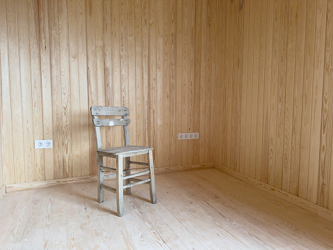 An old wooden chair in a wood-lined room. No people.