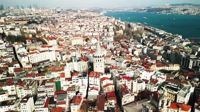 AERIAL Shot of Galata Tower Amidst Buildings In Crowded City By Sea on Sunny Day