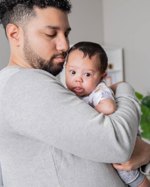 istock Newborn baby boy looks at camera while being held by his young father 2049728193