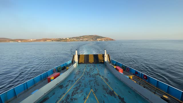 Empty car ferry leaving the Bozcaada port. The ferryboat, which leaves the port with passengers and vehicles, is heading towards the next port of Geyikli in the northern Aegean. No people. Morning on a sunny summer day.