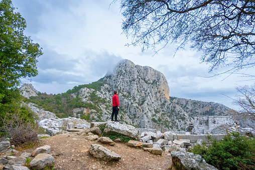 A traveling man exploring ancient cities and nature. He stands with his camera in his hand. Termessos, Antalya