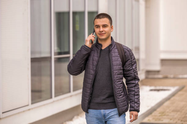 istock Shot of a young man using a mobile phone while walking near the faculty building. 2049838185