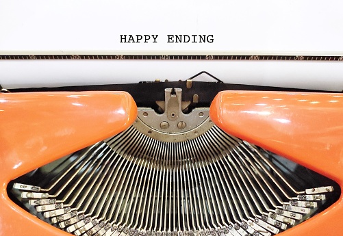 Vintage typewriter with typed text HAPPY ENDING - means ending of story or or events in which the people involved are all happy - when all problems are solved, finish writing a book or a novel