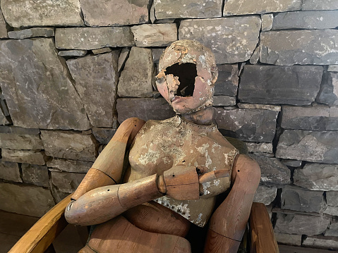 Old dummy doll on the background of stone wall with a hole on its face