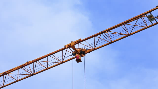 Drone Closeup Shot of Large Yellow Crane Operating at Construction Site Under Blue Sky