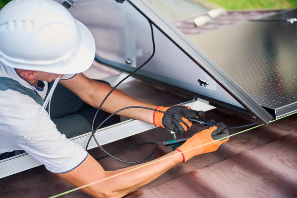 istock Worker installing solar panels system on rooftop of house, wiring solar modules together. 2049932707