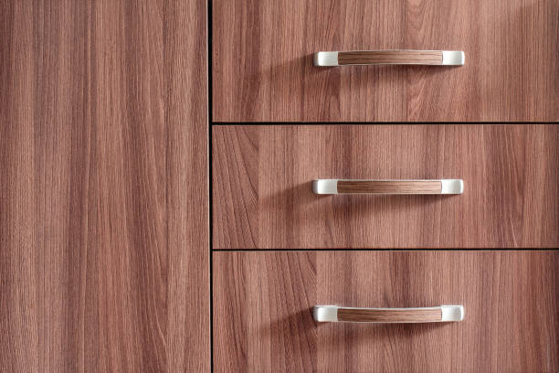 Drawer pulls with silver metal handles in front of a wooden cabinet in the style of complex texture with high detail and asymmetric balance and light silver and dark bronze colors Drawer pulls with silver metal handles in front of wooden cabinet in style of complex texture with high detail and light silver and dark bronze colors. handle stock pictures, royalty-free photos & images