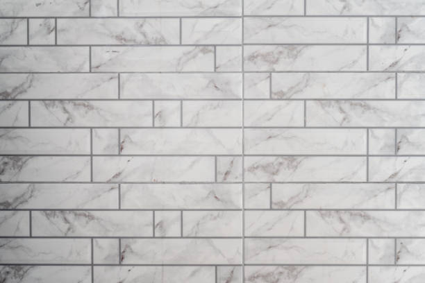 istock White wall with marble tiles and a white background in the style of linear patterns. Bathroom tiled floor is made of white color 2049934340