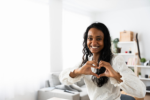 Young black woman doing heart shape with hands. Valentine's day concept with copy space