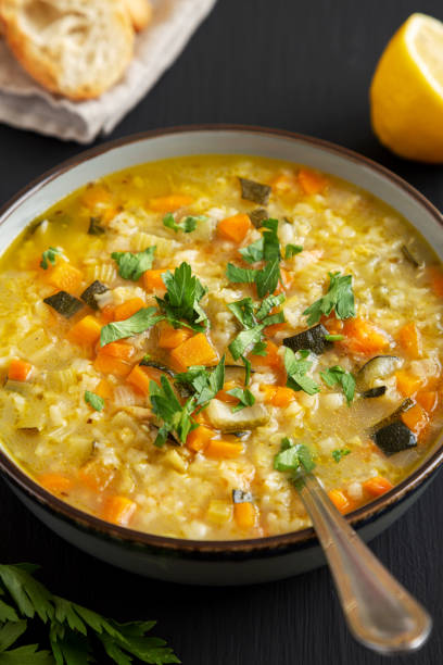istock Homemade fresh lemon rice soup in a bowl on a black surface, side view. Close-up. 2049936535