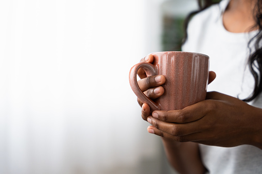 Closeup of hands holding a cup of coffee. Unrecognisable black woman with copy space.