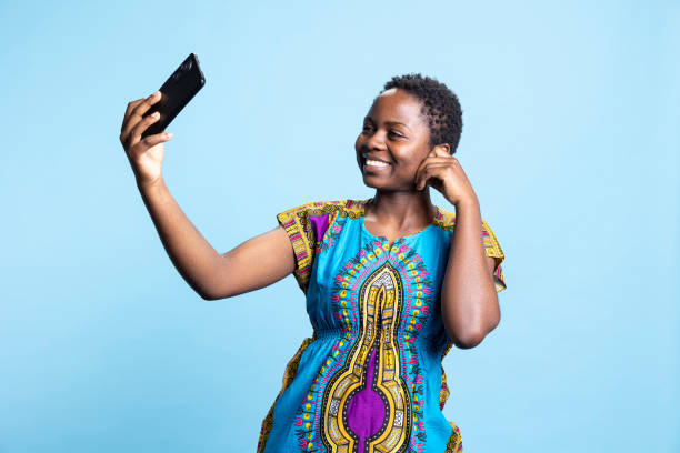 istock African american woman smiling at smartphone camera in studio 2049944472