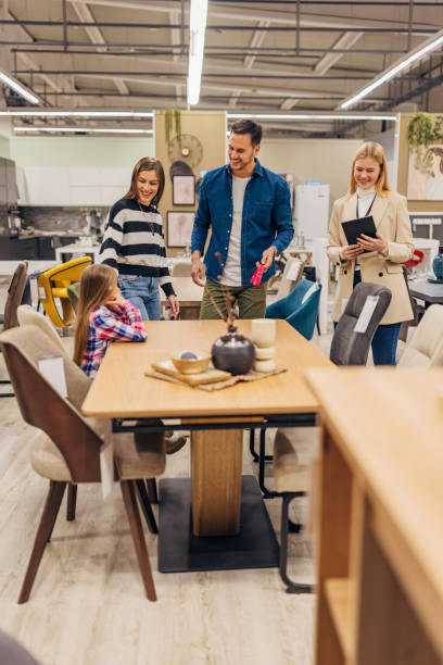 istock Smiling saleswoman helps customers when buying a dining table and chairs 2049954110