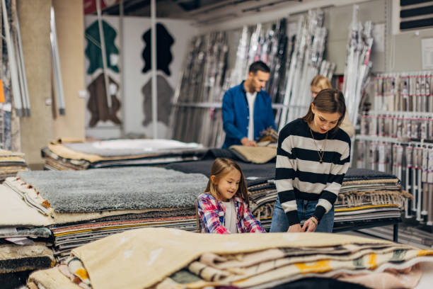 istock Mother and daughter are looking at different types of carpets, while her husband is talking to the saleswoman 2049960481