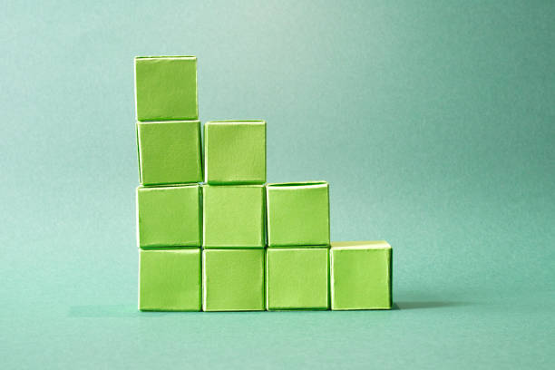 This image showcases a stepwise arrangement of green cubes, creating a visually pleasing ascending stack that mimics a simplified bar chart. Set against a soft teal backdrop, the monochromatic color scheme emphasizes minimalism and modern design. The geometric clarity of the cubes symbolizes structure and growth, making it an ideal representation for concepts such as progress, hierarchy, or eco-friendly development in business and art.