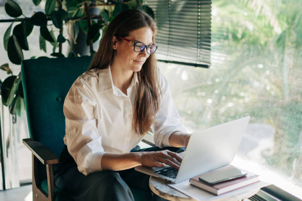 istock Young working woman in a coffee shop with a laptop. Remote work, using a computer application for investing. 2049976825