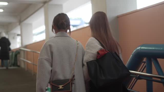In Cheung Chang, Hong Kong, two women stroll away from the camera, both sporting jackets and carrying bagel bag