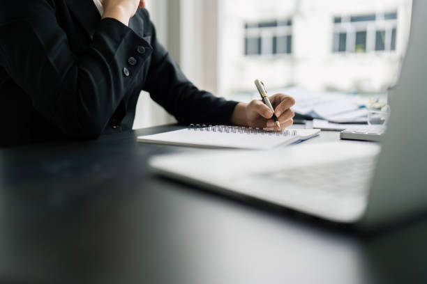 istock Business woman working in office writing plan on note book and use computer laptop to plan marketing strategy 2050008261
