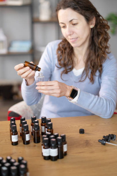 istock Woman Sitting at Table With Bottles of Essential Oils 2050037157
