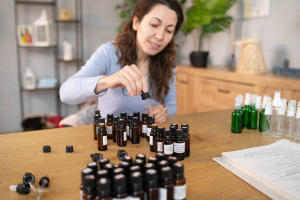 istock Woman Sitting at Table With Bottles of Essential Oils 2050037679