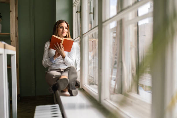 istock Businesswoman Finding Tranquility on Window Sill with Book 2050047989