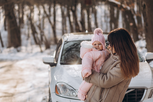 mother and daughter on the background of a white jeep in winter