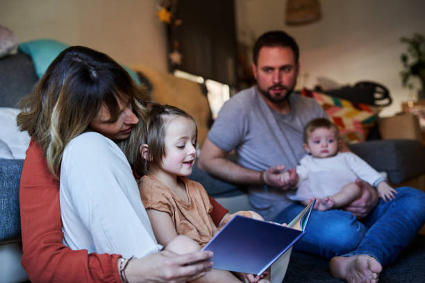 Young family reading storybook together in the living room floor. Young family reading storybook together in the living room floor. real wife stories stock pictures, royalty-free photos & images