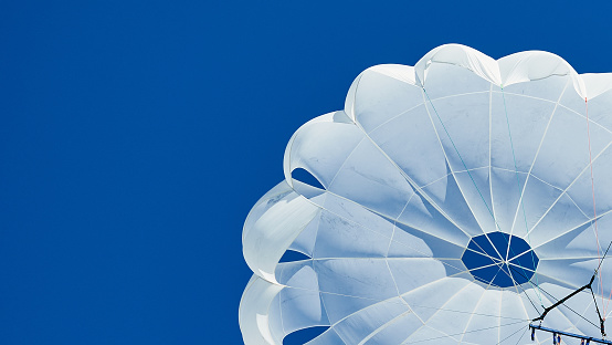 White parachute against a blue sky banner.