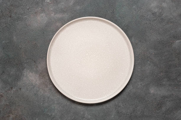 istock Empty beige plate on a dark grunge background. Top view, flat lay, copy space. 2050146478