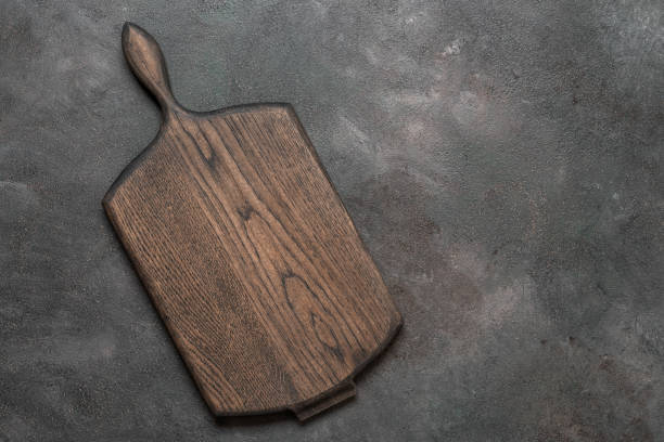 istock Empty wooden cutting board on dark grunge background. Kitchenware. Top view, flat lay. 2050146479