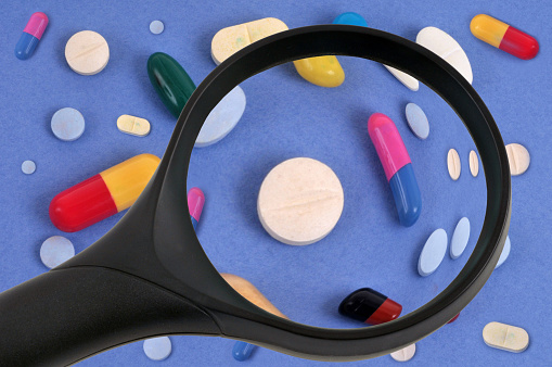 Medicines on a blue background examined with a magnifying glass