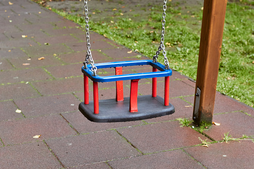 Children's swing on a chain. Plastic swing in blue, red and black colors