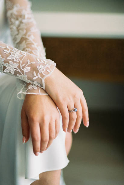 istock Bride in a white lace robe sits with her hands folded on her knees. Cropped. Faceless 2050191998