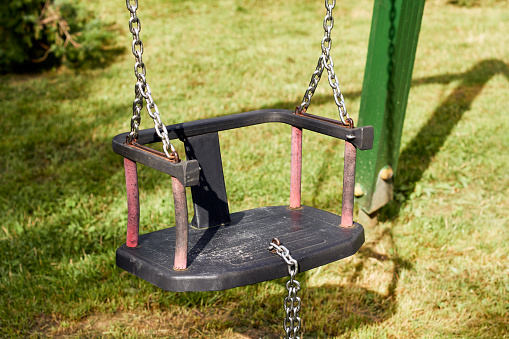 Children's swing on a chain. Plastic swing in dark colors
