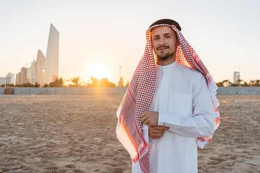 Portrait of a handsome young man wearing keffiyeh and dishdasha on the beach in Kuwait city in Kuwait.