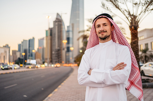 Portrait of a handsome young man wearing keffiyeh and dishdasha on the street in Kuwait city in Kuwait.