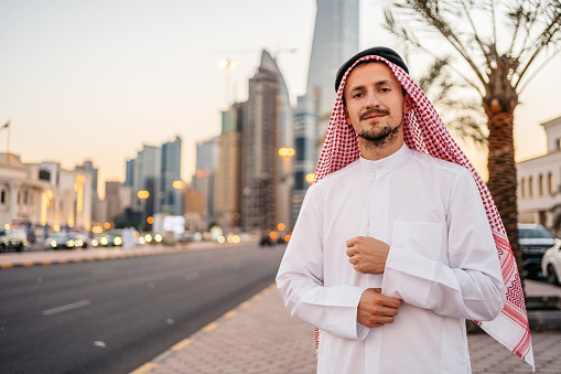 Portrait of a handsome young man wearing keffiyeh and dishdasha on the street in Kuwait city in Kuwait.