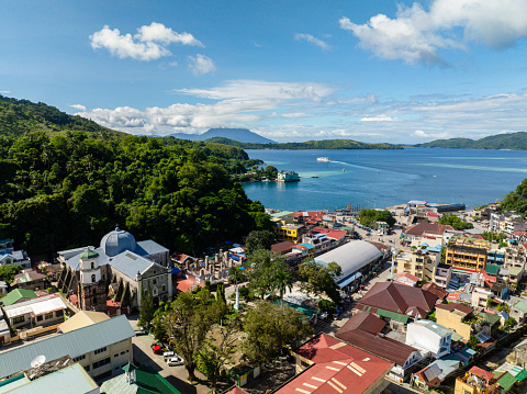 Aerial view of commercial buildings and streets in Romblon Island. Ferry over the blue sea. . Romblon, Philippines.