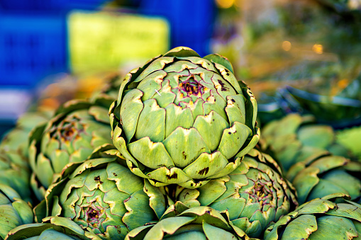 Bunch of artichokes are stacked on top of each other.