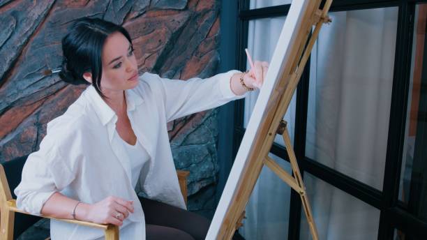 Left-handed artist makes a pencil sketch on canvas