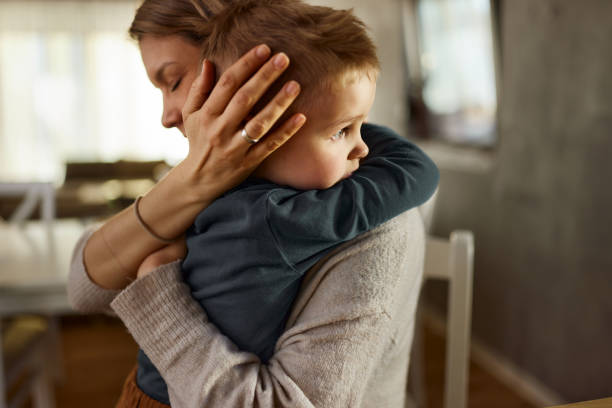 Don't worry sweetie, mommy is here! Single mother consoling her sad little boy at home. one parent stock pictures, royalty-free photos & images