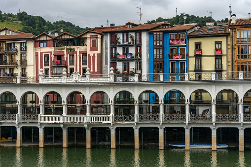 Tolosa, Spain - July 19, 2023: Arcades of the Tinglado market and multicolored buildings in the old town of the city of Tolosa since Oria river, Basque Country, Spain.