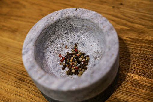 Colorful pepper in mortar. Aromatic spice. Close up.
