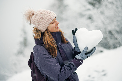 Young woman holding a heart made of snow on a winter day.
Cold winter day. 
Shot with Canon R5